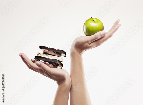 Photo: woman cupping green apple above chocolate bars woman cupping green apple above chocolate bars