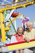 smiling senior couple on amusement park ride