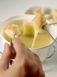 cheese fondue with cubes of bread and hand 