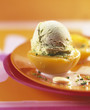 Half a peach topped with a scoop of pistachio ice cream