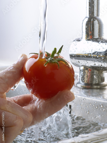 Photo: Rinsing a tomato under the tap water Rinsing a tomato under the tap water