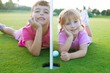 Photo: Golf sister girls relaxed laying green hole ball Golf sister girls relaxed laying green hole ball