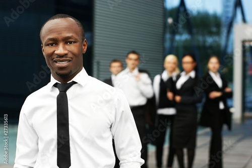 Photo: A young African American businessman in front of his colleagues A young African American businessman in front of his colleagues