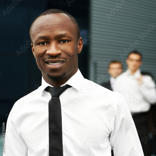 Photo: A young African American businessman in front of his colleagues A young African American businessman in front of his colleagues