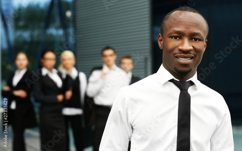 Photo: A young African American businessman in front of his colleagues A young African American businessman in front of his colleagues