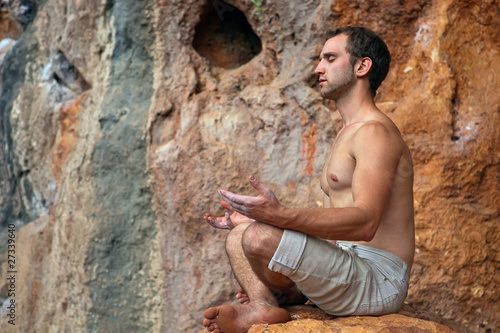 Photo: Young man meditating on rock in the mountains Young man meditating on rock in the mountains