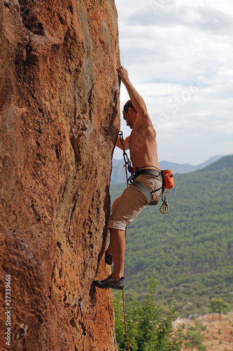 Photo: Rock climber on the cliff with mountainous background Rock climber on the cliff with mountainous background