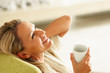 Smiling middle aged woman with a cup of tea or coffee looking up Smiling middle aged woman with a cup of tea or coffee looking up