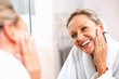 Photo: Happy mature woman admiring herself in the mirror Happy mature woman admiring herself in the mirror
