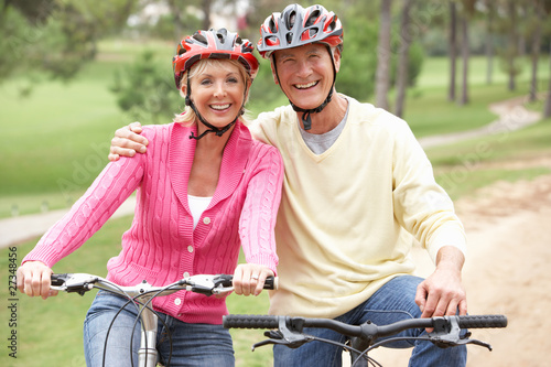 Photo: Senior couple riding bicycle in park Senior couple riding bicycle in park
