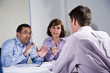 Three mid-adult people sitting at table meeting