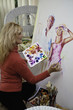 beautiful blond artist in her fifties painting on canvas