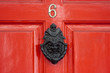 A red wooden door with a large Georgian door knocker