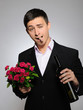 Handsome romantic young man holding rose flower and vine bottle