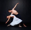 Two ballet dancers performing against black background