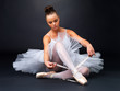 Foto: Young ballerina puts on Pointe against black background Young ballerina puts on Pointe against black background