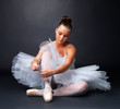 Beautiful ballerina puts on Pointe against black background