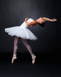 Teenage ballerina performing against black background