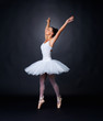 Beautiful ballerina dancing gracefully against black background