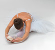 Young ballet dancer stretching against white background