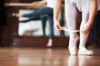 Ballerina puts on Pointe with a blurred man in background