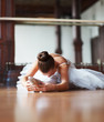 Young ballet dancer stretching on dance floor