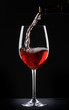 Pouring red wine into a glass over black background Pouring red wine into a glass over black background