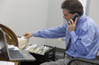 Photo: Businessman looking through his files while on the phone Businessman looking through his files while on the phone