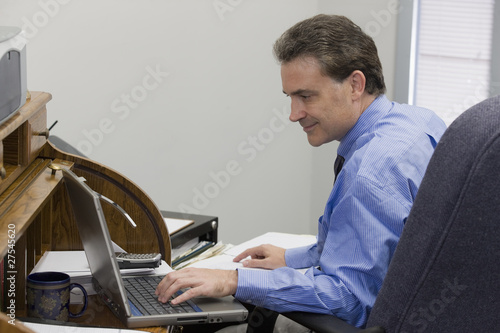 Photo: Businessman working on his laptop and using records Businessman working on his laptop and using records