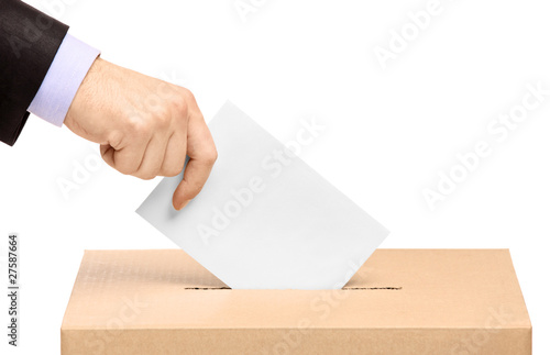 Photo: Hand putting a voting ballot in a slot of box Hand putting a voting ballot in a slot of box