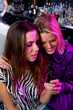 Photo: Friends hanging out at a club looking at a cellular phone Friends hanging out at a club looking at a cellular phone