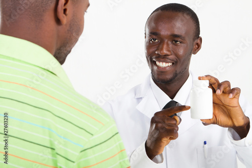 Photo: happy african pharmacist prescribing medicine happy african pharmacist prescribing medicine