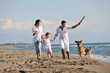 Photo: happy family playing with dog on beach happy family playing with dog on beach