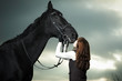 Beautiful young woman with a black horse