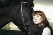 Beautiful young woman with a black horse