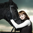 Beautiful young woman with a black horse