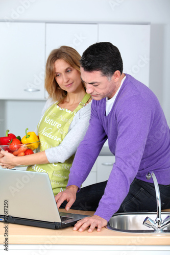 Photo: Couple in kitchen looking for cooking receipe Couple in kitchen looking for cooking receipe
