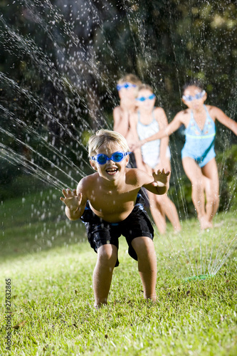 Photo: Boy with friends splashing in lawn sprinkler Boy with friends splashing in lawn sprinkler