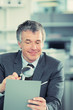 Photo: Businessman looking magnifying glass at newspaper excitedly Businessman looking magnifying glass at newspaper excitedly