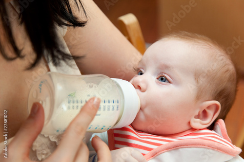 Photo: a mother is feeding her baby from a bottle a mother is feeding her baby from a bottle