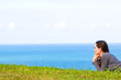 A sad and depressed young woman lying in grass by the ocean