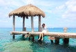 girl sitting on a wooden pier in the caribbean