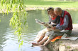 Großvater und Enkelin beim Zeitung lesen am Teich im Grünen Großvater und Enkelin beim Zeitung lesen am Teich im Grünen
