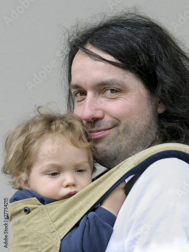 Photo: Father carries his son in sling baby carrier Father carries his son in sling baby carrier