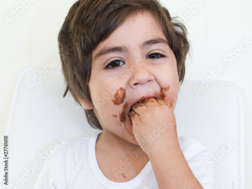 Photo: bambino con mani in bocca piene di cioccolato bambino con mani in bocca piene di cioccolato