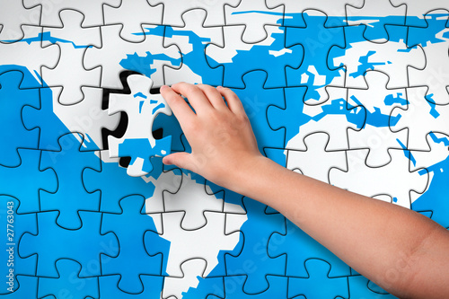 Illustration: Child's hand inserting piece of jigsaw puzzle into the map hole Child's hand inserting piece of jigsaw puzzle into the map hole
