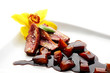 Sliced duck meat with pieces of peach and balsamic sauce
