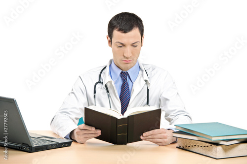 Photo: A male doctor reading a book in his office A male doctor reading a book in his office