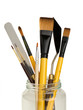 Paintbrushes and palet knifes in a glass jar