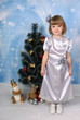 cute girl in a silver dress around Christmas tree